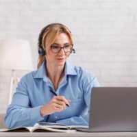 Online consultation with psychologist. Woman with glasses and headphones looks at laptop